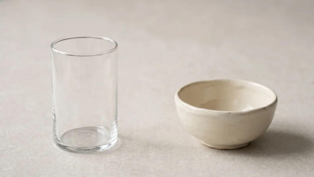 Blankt glas og håndlavet mat keramikskål side om side på lys sten